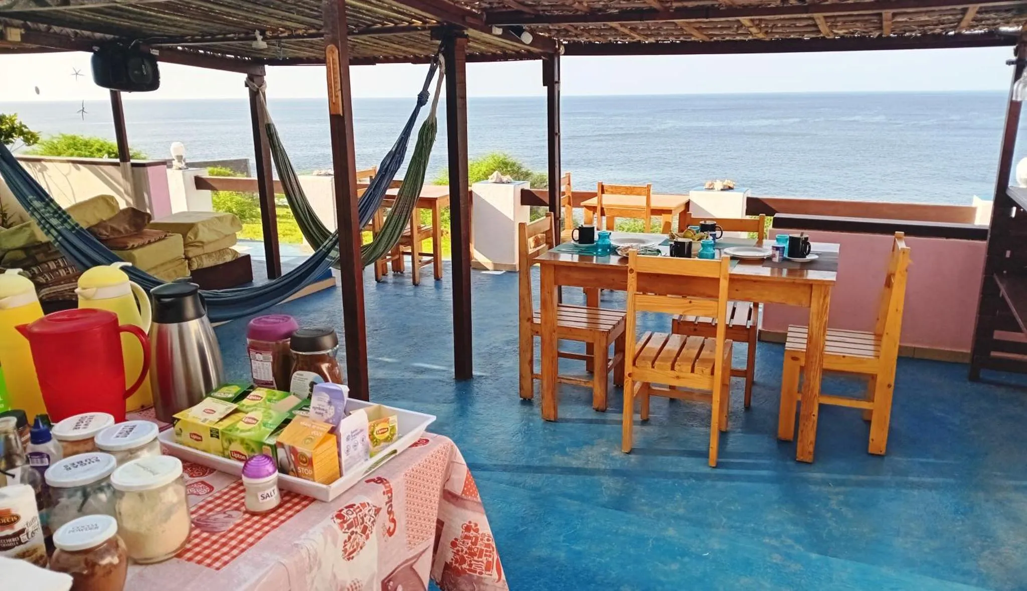 Une terrasse avec un coin repas et des hamacs offre une vue sur la mer.