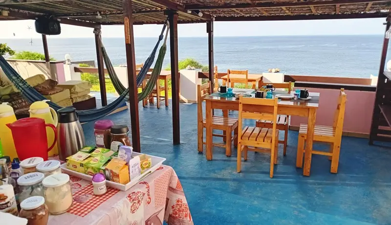 Une terrasse avec un coin repas et des hamacs offre une vue sur la mer.