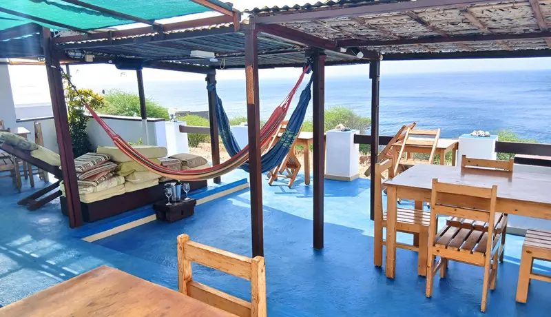 Espace de détente extérieur avec hamacs et mobilier de jardin face à la mer.