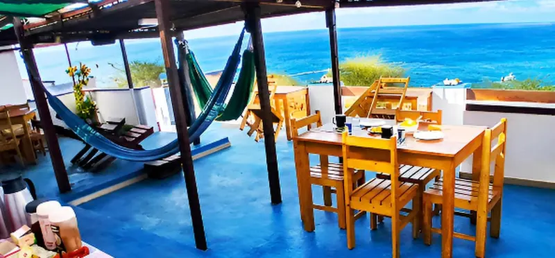 Espace de détente extérieur avec tables et hamacs face à la mer.