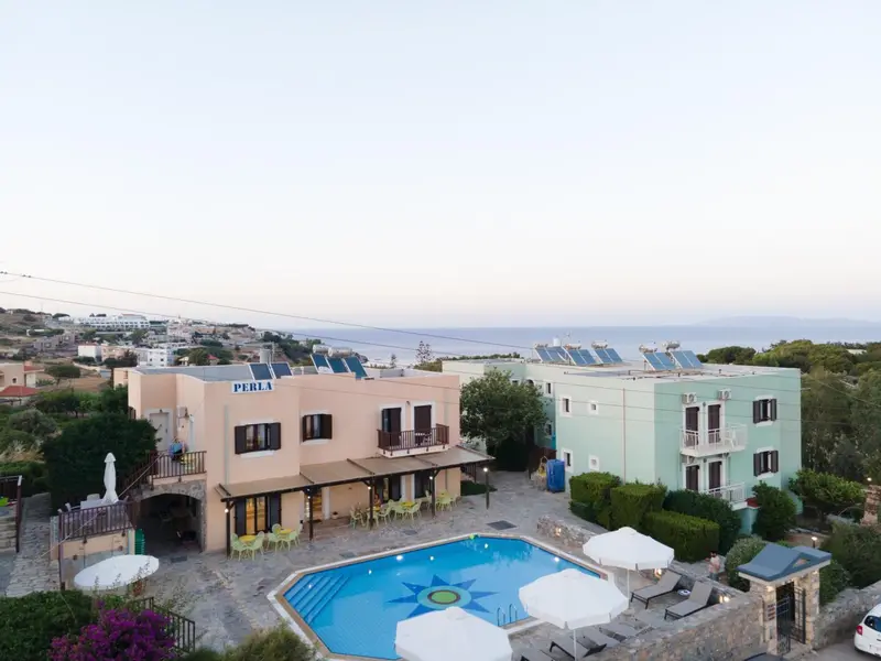 Bâtiment blanc et turquoise avec piscine et végétation luxuriante, vu d'en haut.