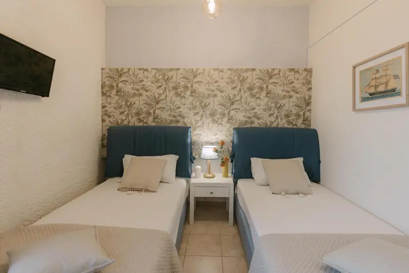 Une chambre lumineuse avec deux lits simples et une décoration murale à motifs végétaux.