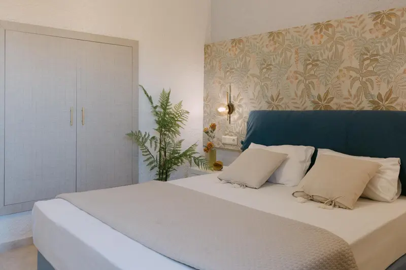 Une chambre lumineuse avec un grand lit et un décor floral.