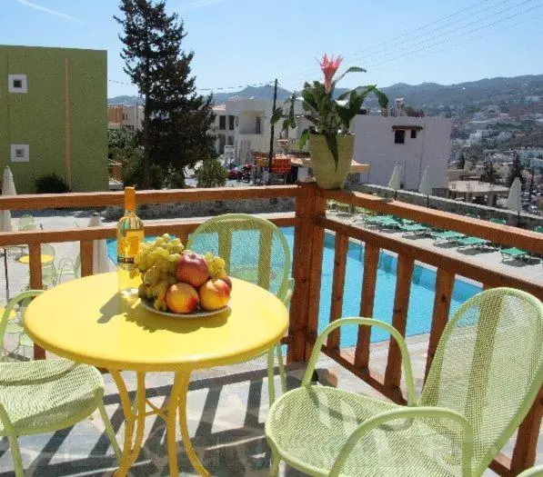 Une table jaune avec des fruits et une bouteille sur une terrasse ensoleillée.