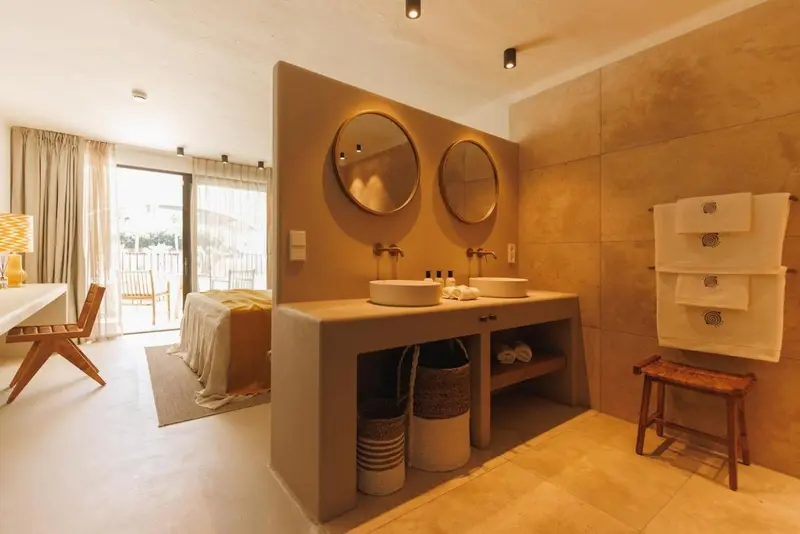 Une salle de bain lumineuse avec deux vasques et des miroirs ronds.