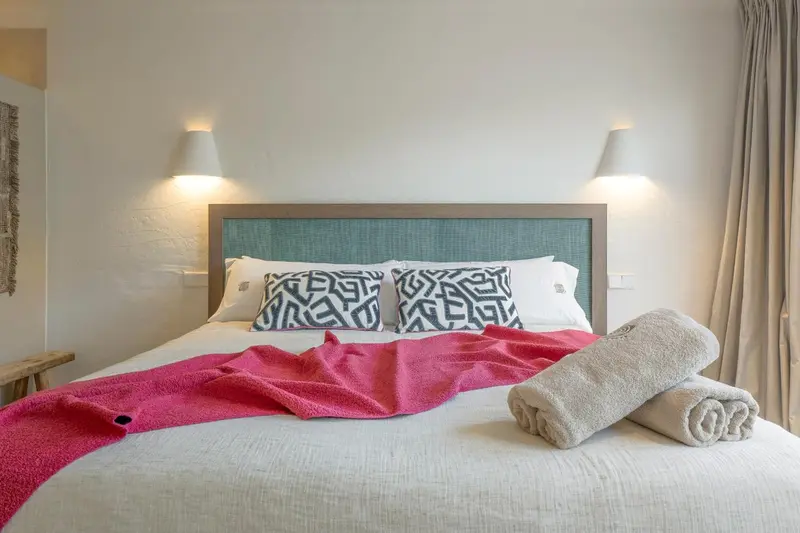 Un lit double est fait avec des oreillers et une couverture rose.