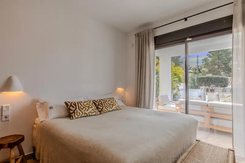 Une chambre lumineuse avec un grand lit et un accès à une terrasse.