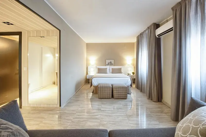 Une chambre lumineuse avec un grand lit et un coin salon.
