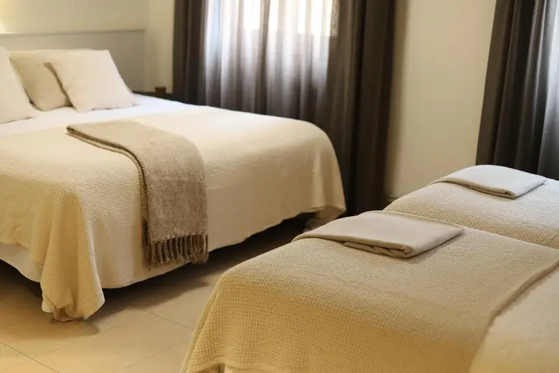 Une chambre lumineuse avec deux lits simples recouverts de plaids.