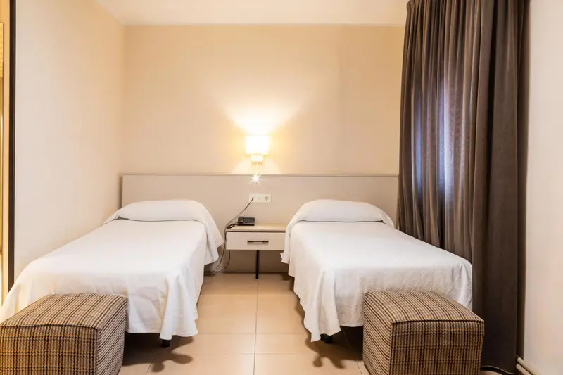 Une chambre avec deux lits simples et une table de chevet.
