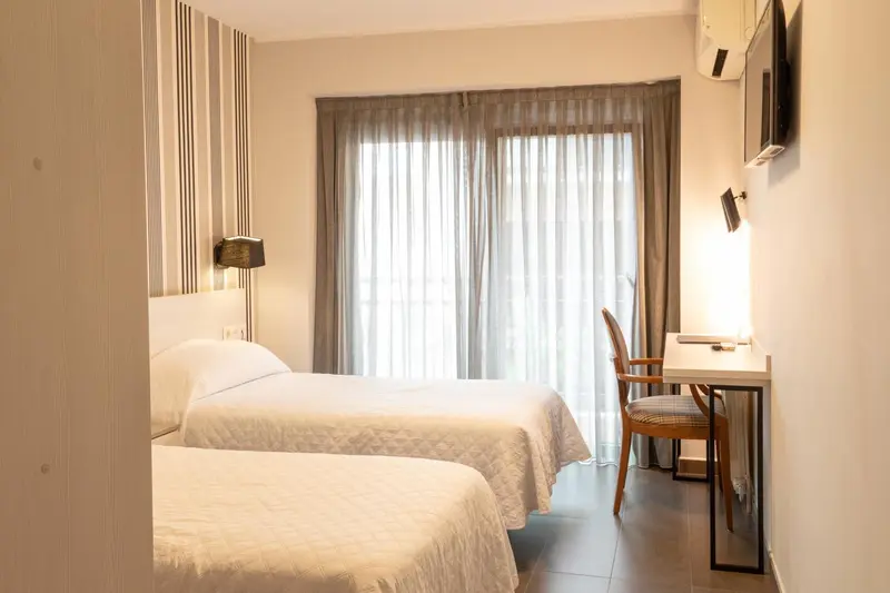 Une chambre lumineuse avec deux lits simples et un bureau.