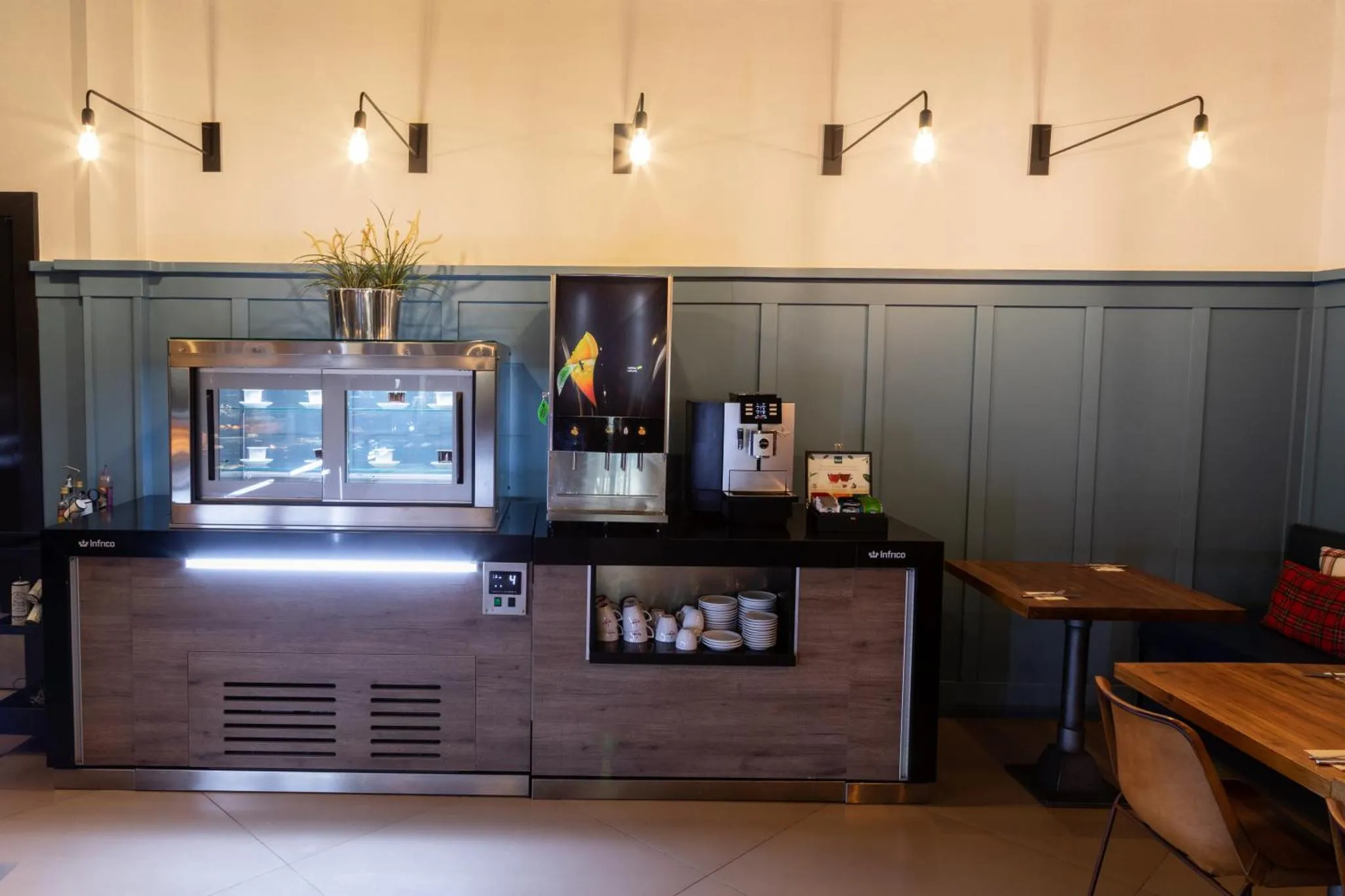 Un comptoir de boissons et pâtisseries est présenté dans un espace lumineux.