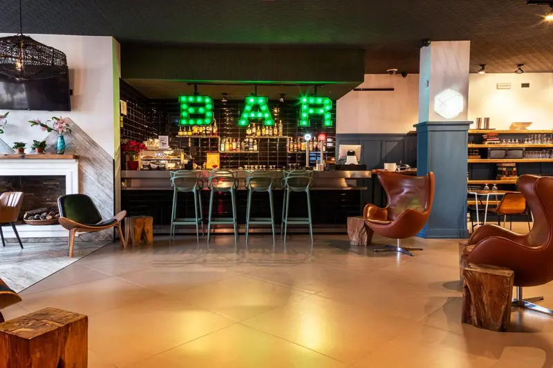 Un bar lumineux avec des tabourets et des fauteuils confortables.