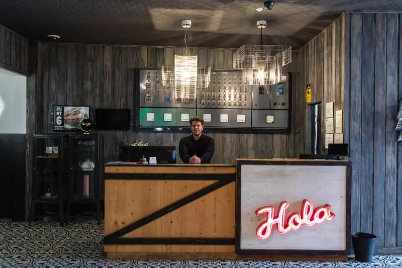 Un comptoir d'accueil en bois avec un employé derrière.
