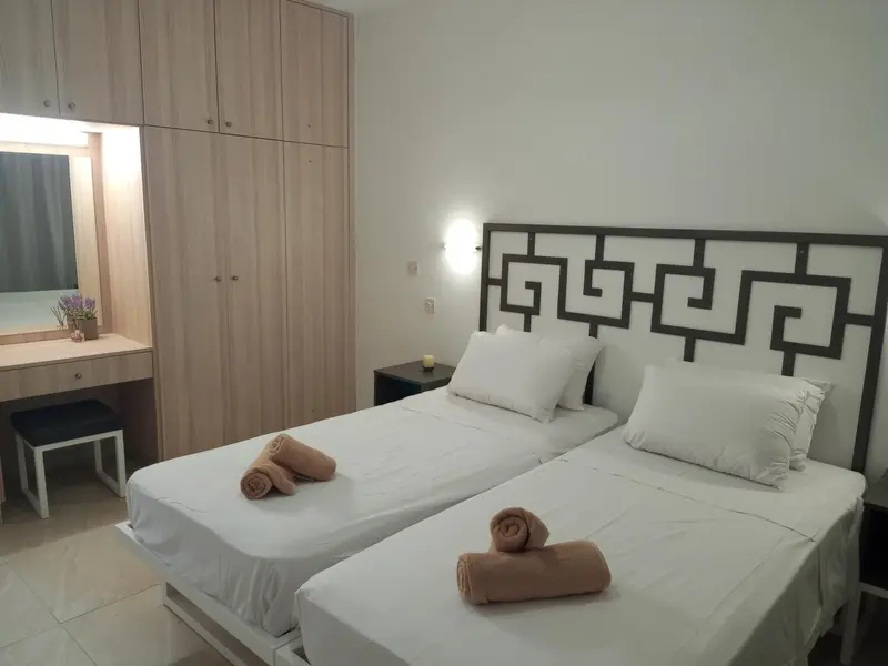 Une chambre lumineuse avec deux lits simples et un grand placard.