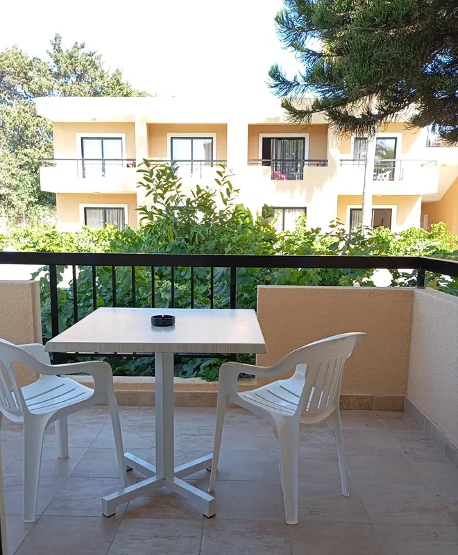 Terrasse avec table et chaises en plastique devant un bâtiment blanc.