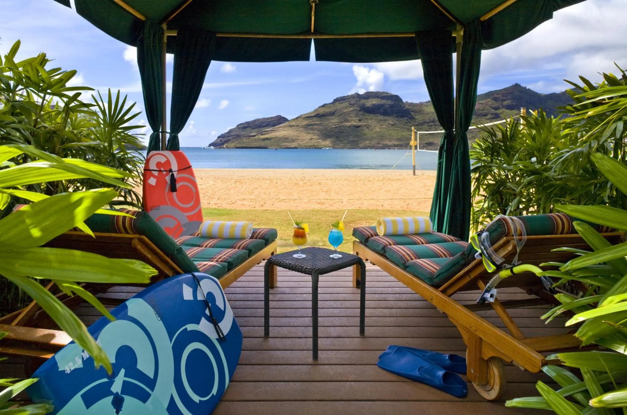 Deux transats colorés invitent à la détente sur une terrasse en bois face à la mer.