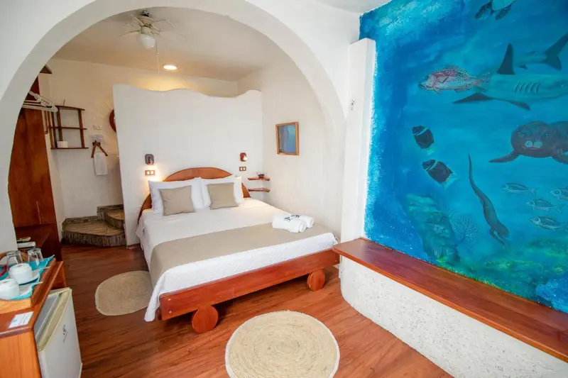 Une chambre lumineuse avec un lit et un mur décoré d'une scène marine.