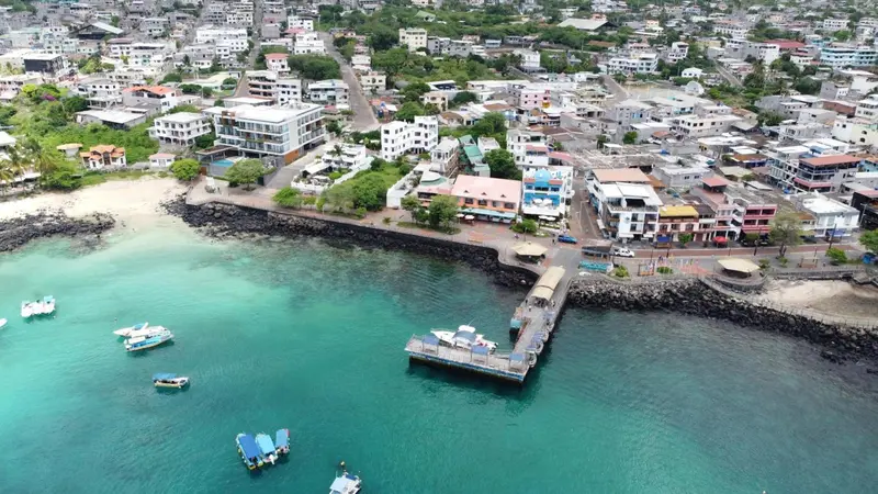 Vue aérienne d'une ville côtière avec des bateaux dans une baie turquoise.