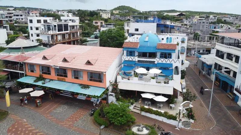 Vue aérienne d'un ensemble de bâtiments colorés avec des terrasses et des parasols.