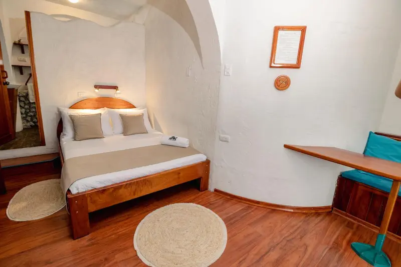 Une chambre lumineuse avec un lit double et un petit bureau.