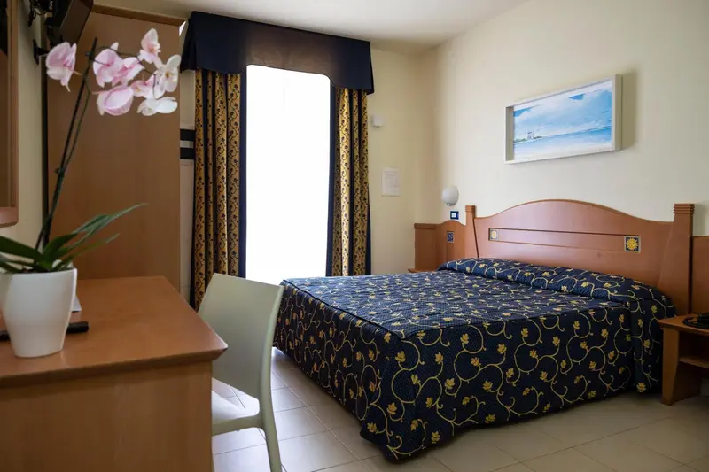 Une chambre lumineuse avec un lit recouvert d'une couverture à motifs et un tableau mural.