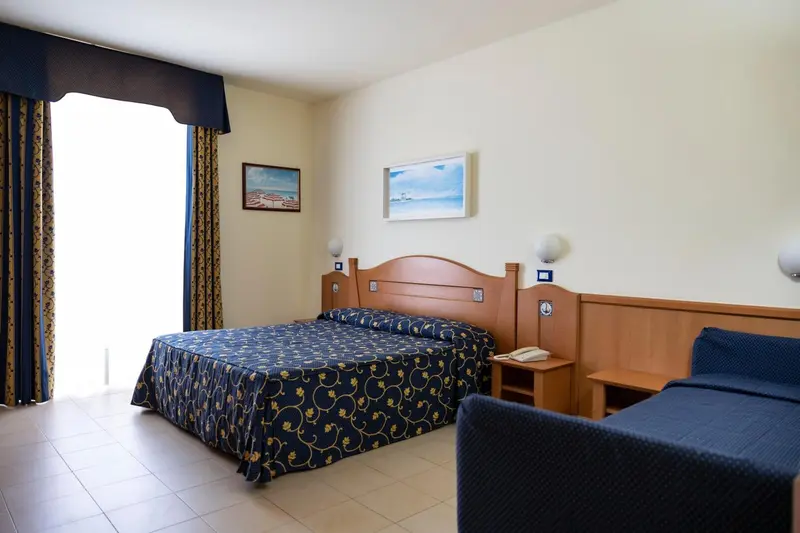 Une chambre lumineuse avec un grand lit recouvert d'une courtepointe à motifs.