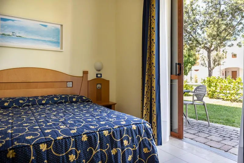 Une chambre lumineuse avec un lit double et un accès à une terrasse.