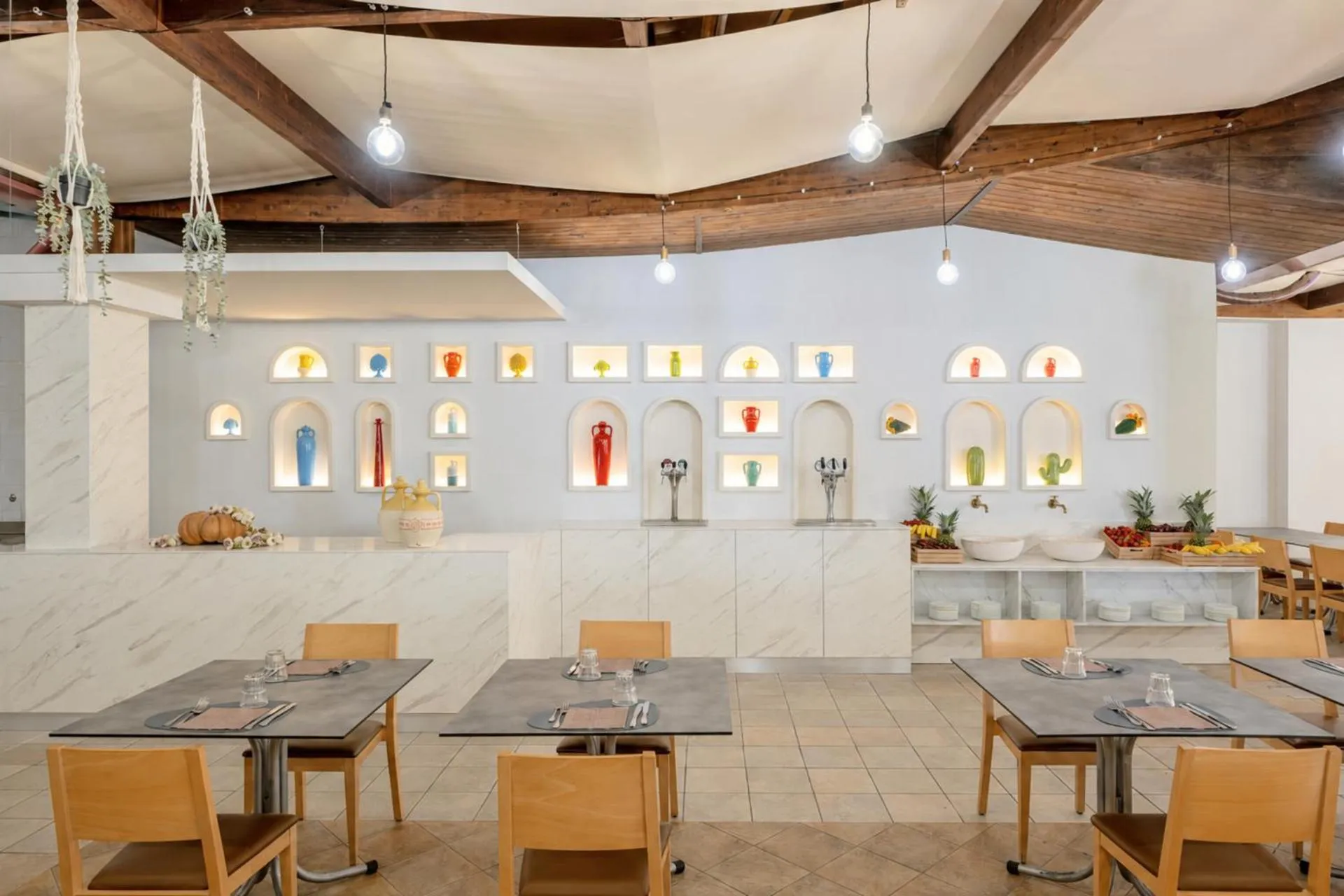 Une salle lumineuse avec des tables dressées et un long comptoir blanc.