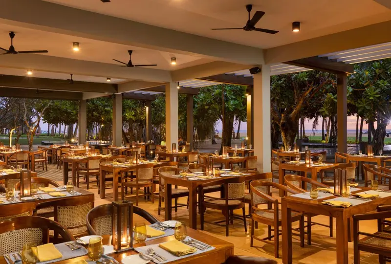 Une salle à manger extérieure avec des tables dressées pour le dîner.