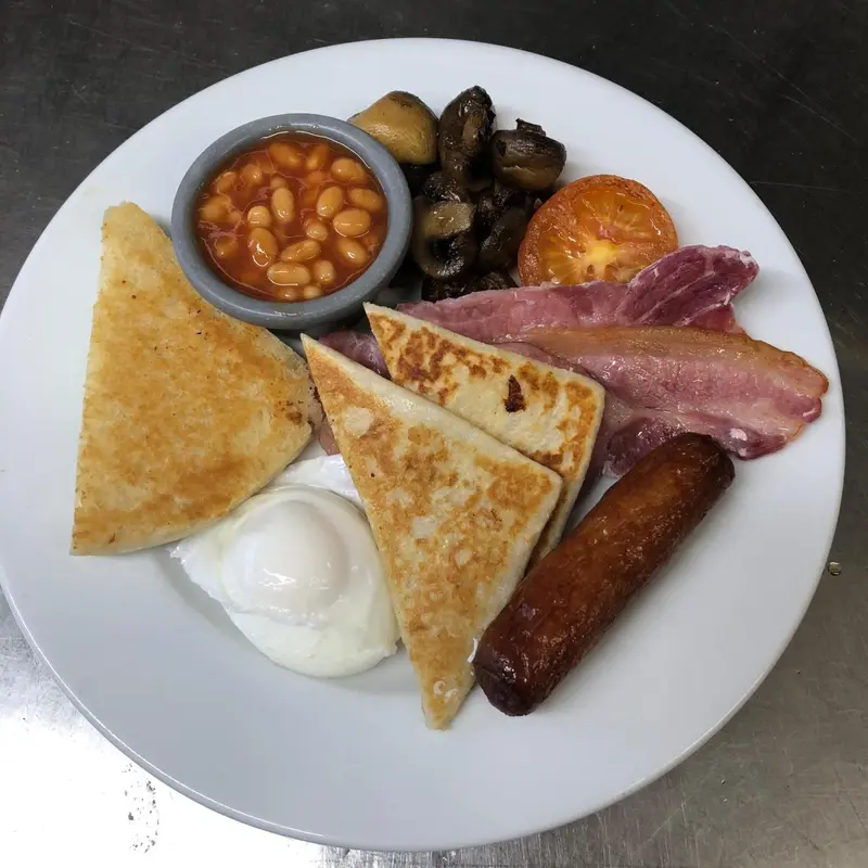 Assiette copieuse avec œufs, haricots, champignons, tomates, bacon et saucisse.