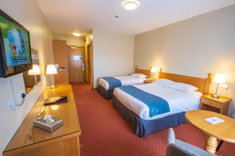 Une chambre d'hôtel avec deux lits simples et une télévision murale.