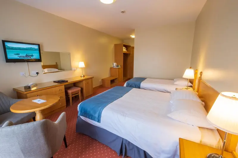 Une chambre d'hôtel lumineuse avec deux lits simples et un coin salon.