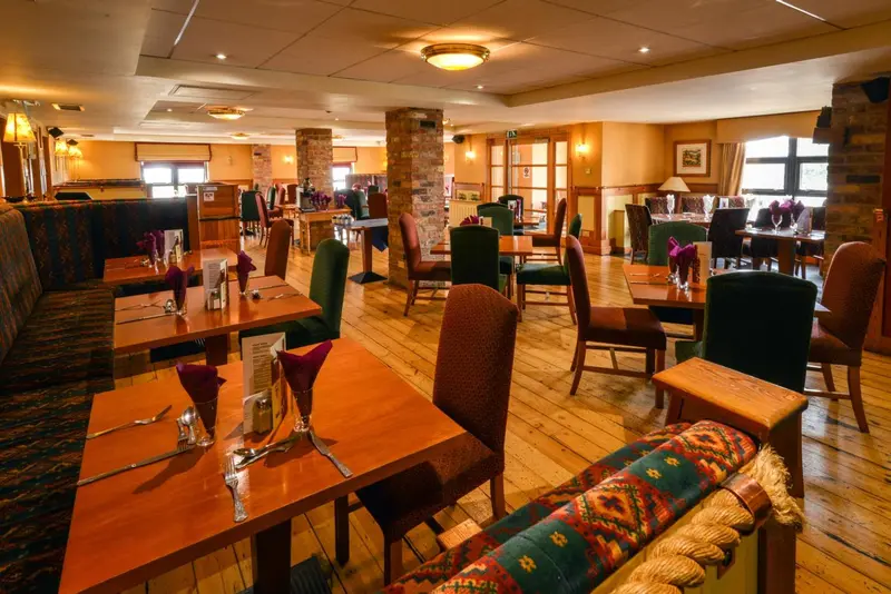 Une salle de restaurant lumineuse avec des tables dressées et des banquettes.