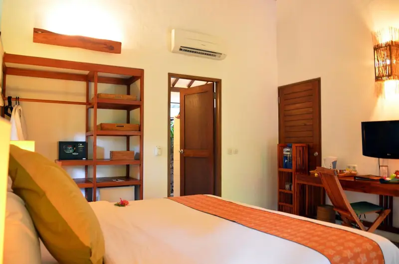 Une chambre lumineuse avec un lit recouvert d'un plaid orange et un bureau en bois.