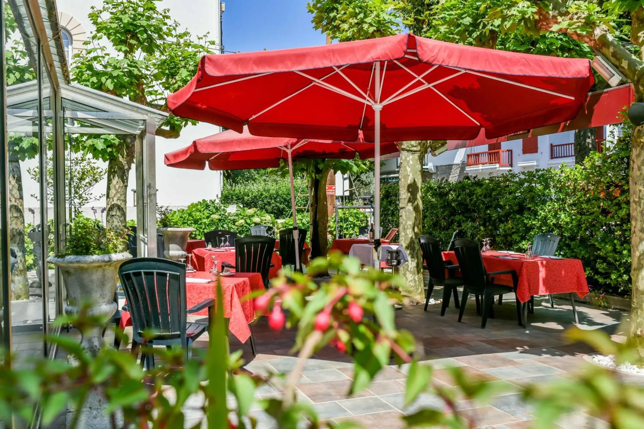 Terrasse ombragée avec tables dressées pour un repas en extérieur.