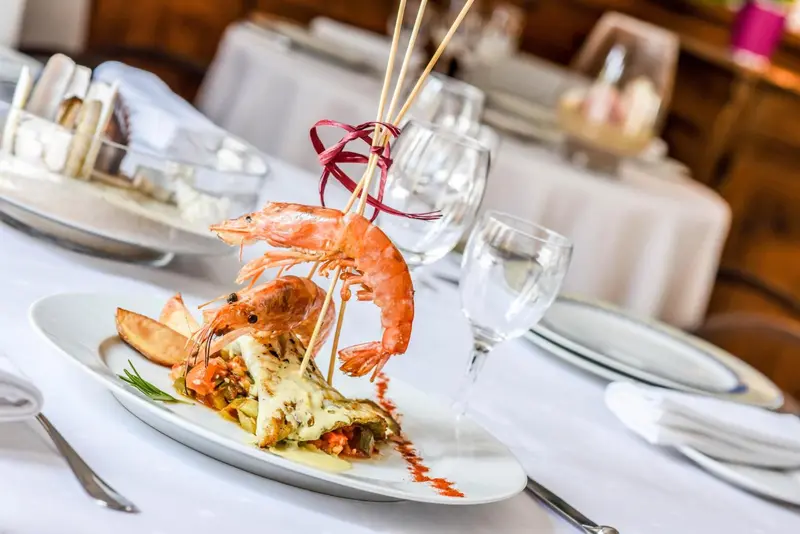 Assiette de crevettes et de légumes présentés avec soin sur une table nappée.