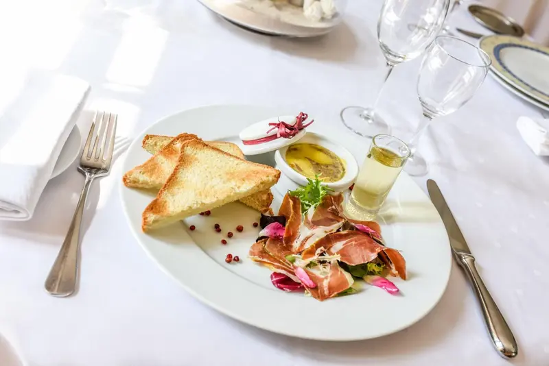 Assiette de hors-d'œuvre avec toasts, jambon cru et sauce.