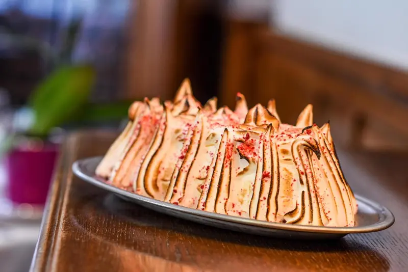 Un dessert crémeux surmonté d'une meringue grillée est présenté sur une assiette.