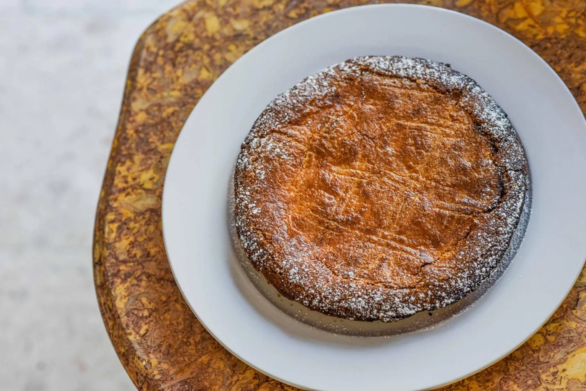 Une part de gâteau saupoudrée de sucre glace est présentée sur une assiette.