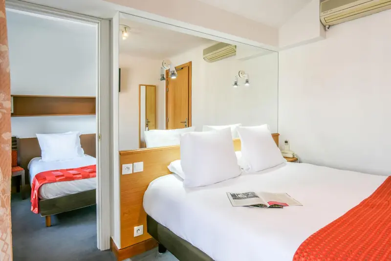 Une chambre avec deux lits simples et un miroir mural.