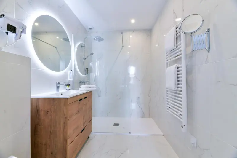 Une salle de bain moderne avec douche à l'italienne et miroir lumineux.