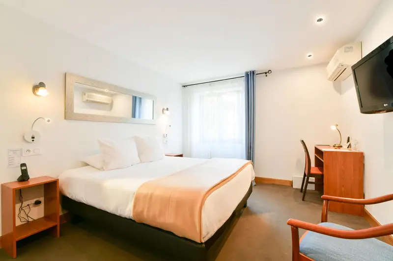 Une chambre d'hôtel lumineuse avec un lit double et un bureau.