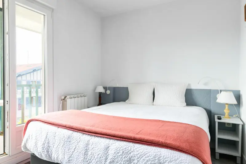 Une chambre lumineuse avec un lit recouvert d'une couverture colorée et des lampes de chevet.