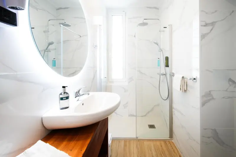 Une salle de bain moderne avec douche à l'italienne et vasque blanche.