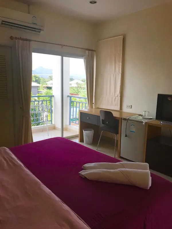 Une chambre avec un lit mauve et une vue sur un paysage verdoyant.