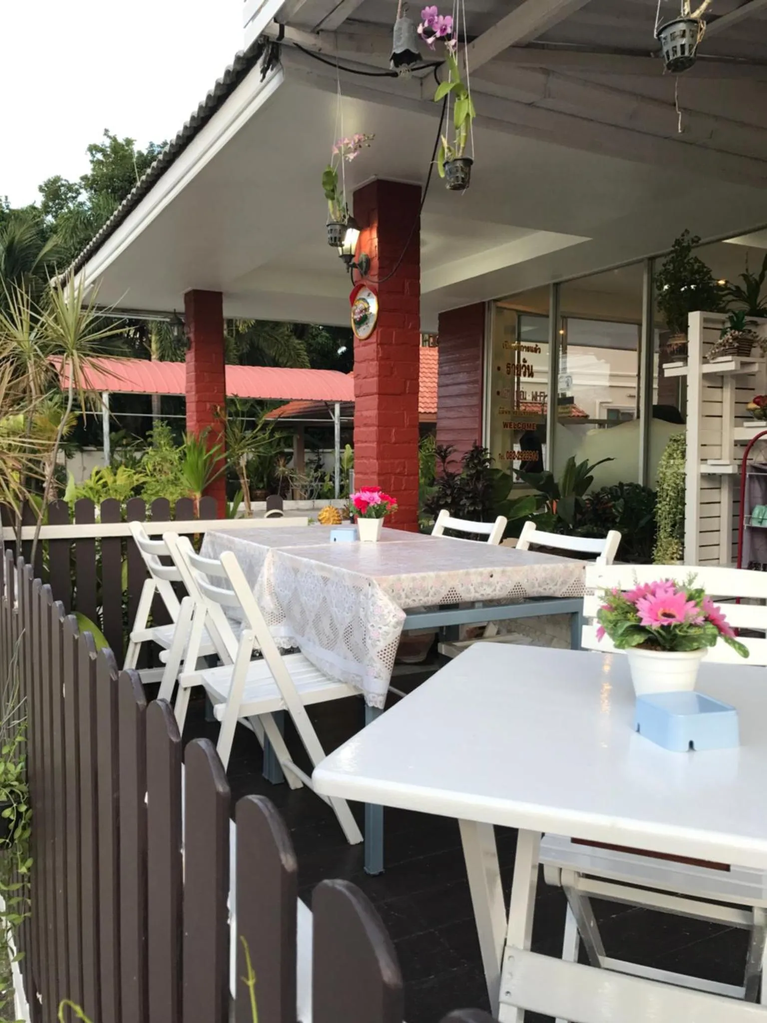 Tables blanches dressées sur une terrasse ombragée avec des plantes en pots.