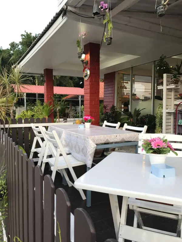 Tables blanches dressées sur une terrasse ombragée avec des plantes en pots.