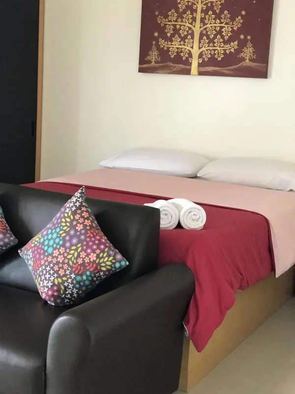 Une chambre avec un lit recouvert d'une courtepointe rouge et un canapé noir.