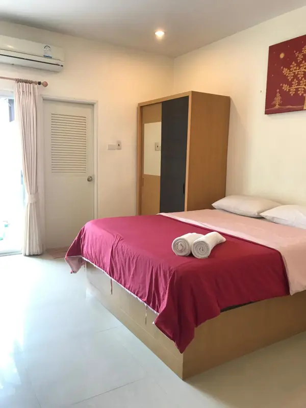 Une chambre lumineuse avec un grand lit recouvert d'une courtepointe rouge.